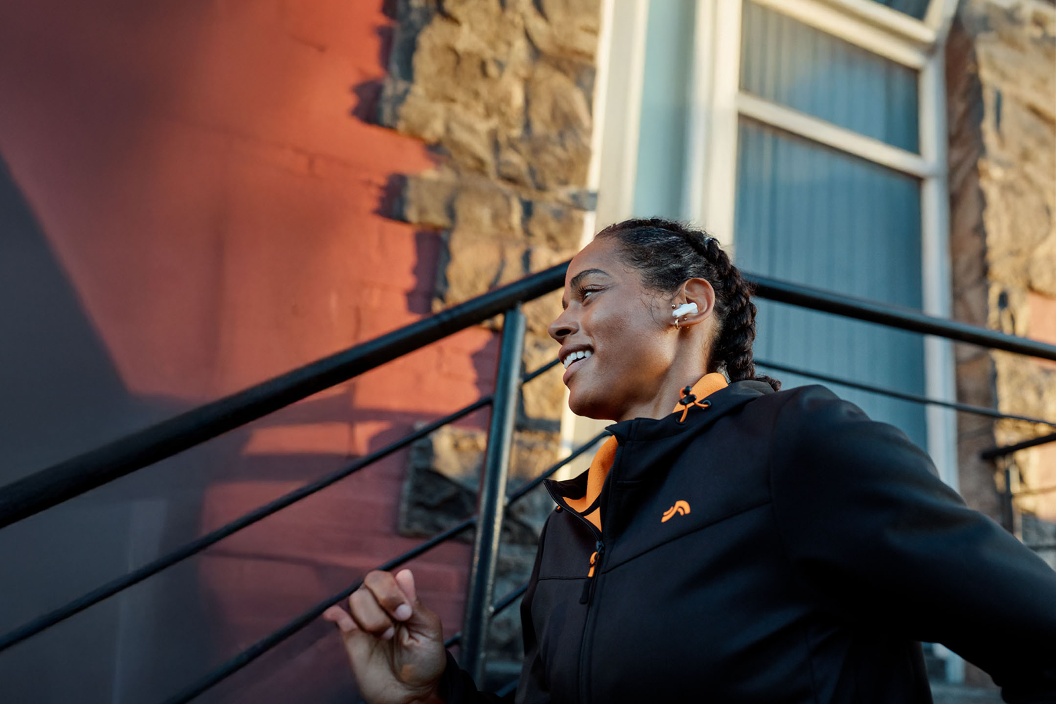 Nainen juoksee kuulokkeet korvissaan takissa.