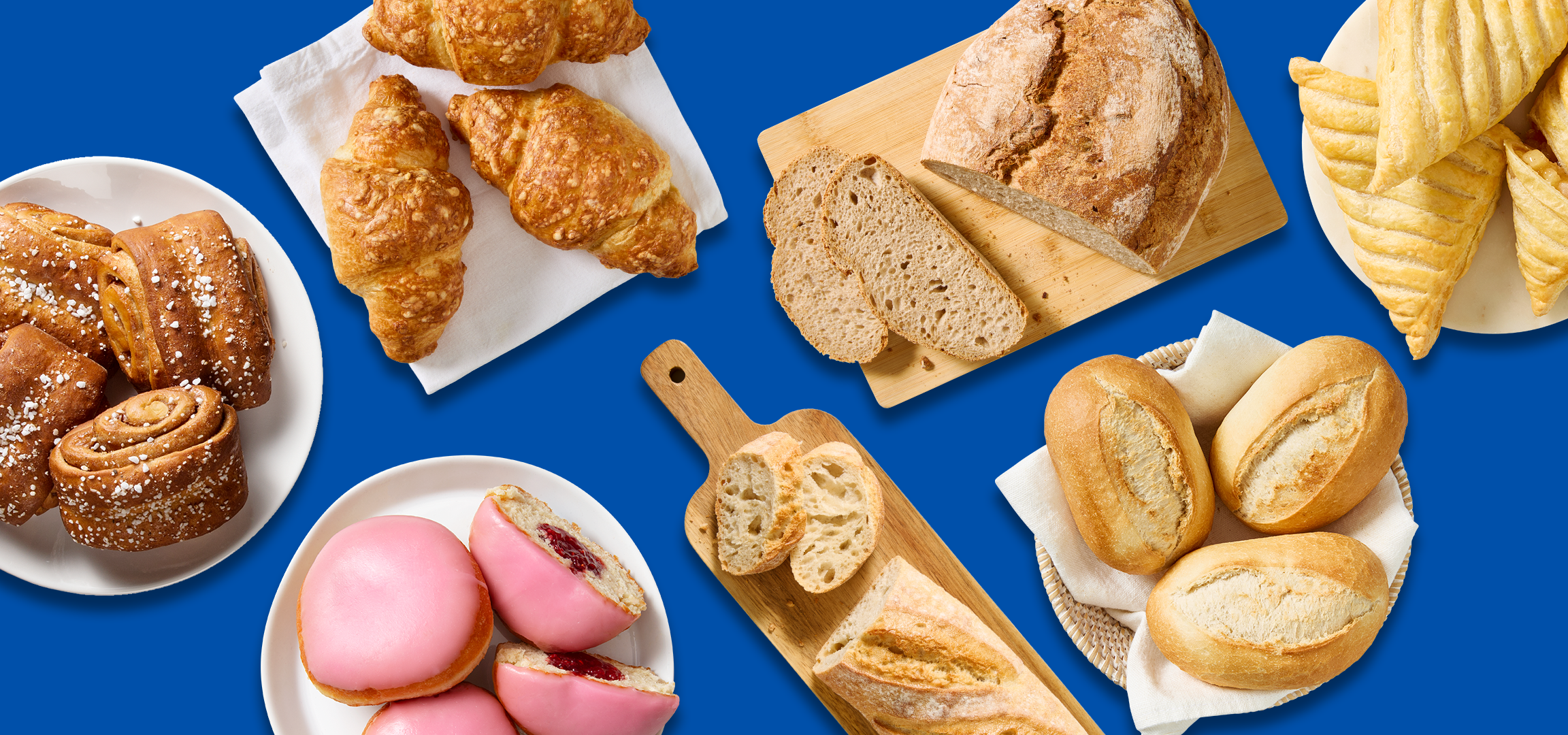 Valikoima leivonnaisia ja leipiä sinisellä taustalla, mukaan lukien kanelipullia, croissanteja ja patonkeja.