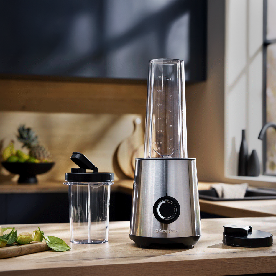 Hopeanvärinen tehosekoitin ja kaksi läpinäkyvää pulloa keittiön työtasolla.